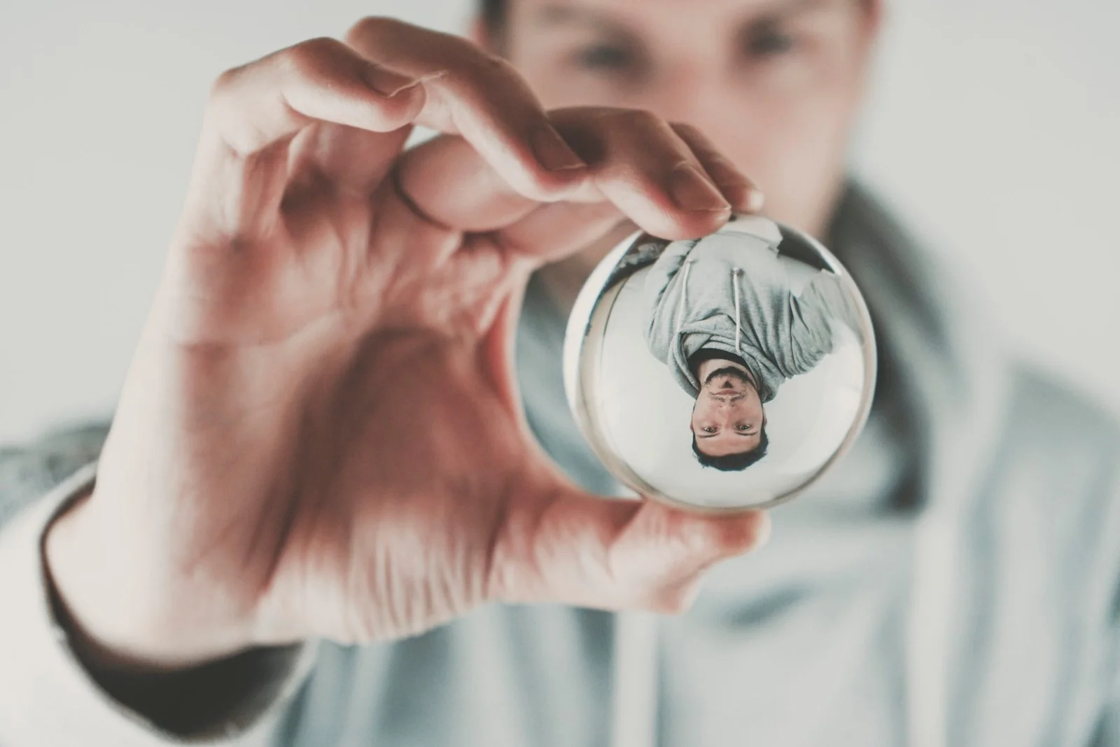 Joven sosteniendo una bola de cristal en la cual se refleja su imagen